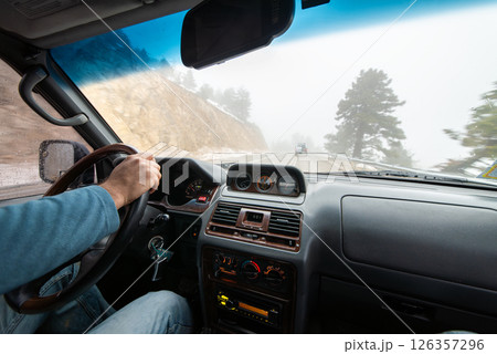 Close-up of man driving car on road. 126357296