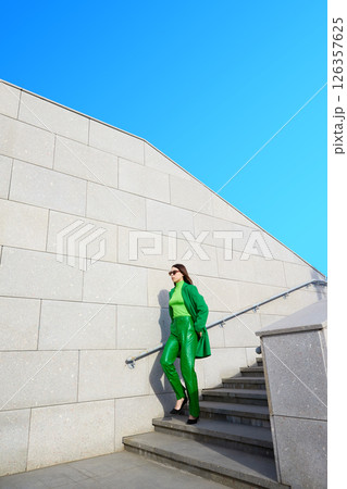 High fashion photo of a young brunette woman in green coat, poloneck and leather pants. High fashion photo of a young brunette woman in green coat, poloneck and leather pants. 126357625
