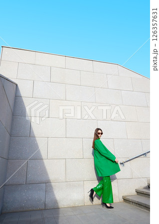 High fashion photo of a young brunette woman in green coat, poloneck and leather pants. High fashion photo of a young brunette woman in green coat, poloneck and leather pants. 126357631