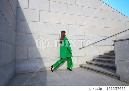 High fashion photo of a young brunette woman in green coat, poloneck and leather pants. 126357633