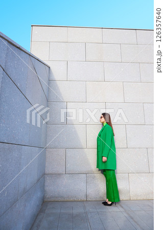 High fashion photo of a young brunette woman in green coat, poloneck and leather pants. High fashion photo of a young brunette woman in green coat, poloneck and leather pants. 126357640