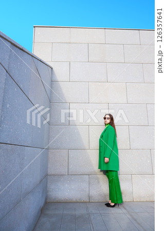High fashion photo of a young brunette woman in green coat, poloneck and leather pants. 126357641