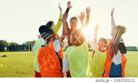 Hands up, soccer and coach in huddle with happy kids on field for motivation, game plan or strategy. Excited, training and practice with children in celebration for sports, football player or support 126358123