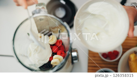 Fruit smoothie, hands and yogurt in blender for breakfast shake, meal replacement and healthy nutrition. Above, machine and preparation in kitchen for weight loss beverage, person diet and wellness 126358315