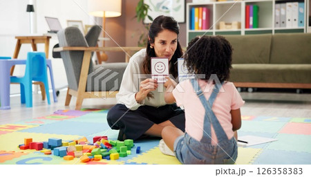 Woman, girl and card with therapy for emotion, choice and happy emoji for mental health assessment on floor. Paper, therapist and child with decision for feelings, sign and evaluation at clinic 126358383