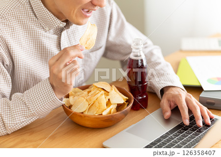 ポテトチップスを食べながら仕事をするミドル男性 126358407