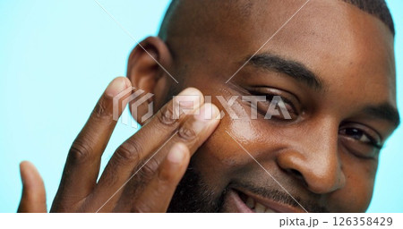Portrait, man and skincare for beauty in studio, healthy skin or moisturizer on blue background. Face, treatment and grooming with African person applying cosmetics, dermatology and hydration facial 126358429