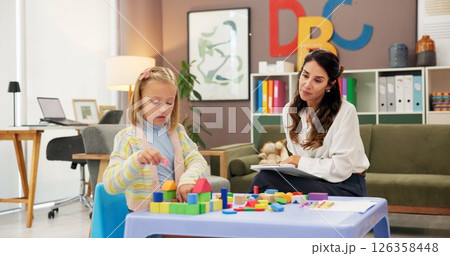 Exam, kid and building blocks with woman in psychology for consulting, child development or play therapy. Education therapist, advice and mental health evaluation with person and girl with toys 126358448