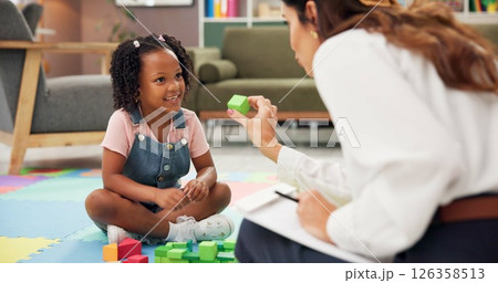 Child, psychologist or blocks with toys for education or childhood development at therapist office. Female person, kid or elementary student with smile for fun activity, shape or learning difficulty 126358513