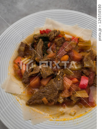Delicious beef stew with carrots, celery, tomatoes and spices, served on injera, a traditional ethiopian flatbread Delicious beef stew with carrots, celery, tomatoes and spices, served on injera, a traditional ethiopian flatbread 126358580