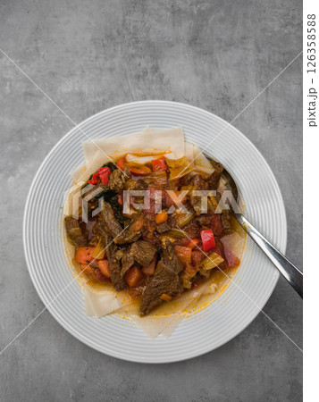 Hearty beef stew nestled alongside spongy injera, accompanied by bright vegetable medley highlighting ethiopian culinary traditions background wallpaper copy space Hearty beef stew nestled alongside spongy injera, accompanied by bright vegetable medley highlighting ethiopian culinary traditions background wallpaper copy space 126358588