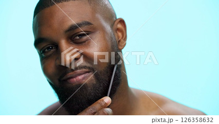Face, black man and beard with comb for styling, beauty with haircare and cosmetics on blue background. Facial hair, self care and healthy glow with brushing on studio, dermatology and grooming 126358632
