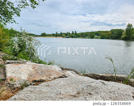 Granite stones overlooking calm lake on cloudy day Hostivar Dam Beach in Prague 126358669