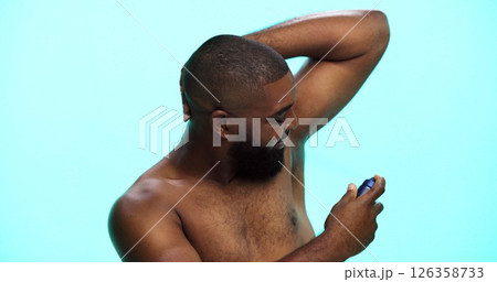 Black man, spray or deodorant for armpit with hygiene in studio, fragrance or grooming with cosmetic product. Underarm smell, perfume or spritz for scent, male person and self care on blue background 126358733