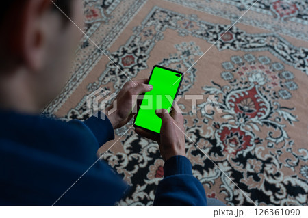 Guy is sitting with a smartphone in his hands with the green screen Guy is sitting with a smartphone in his hands with the green screen 126361090