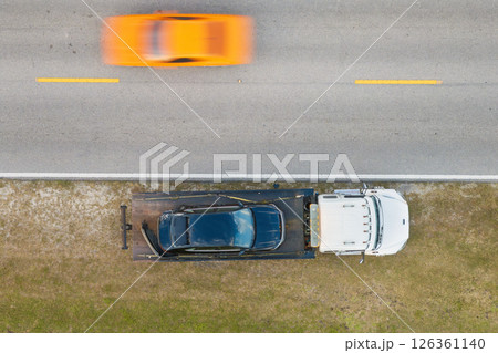 Traffic accident with tow truck hauling smashed vehicle on car crash site. First responders helping on road emergency in Florida Traffic accident with tow truck hauling smashed vehicle on car crash site. First responders helping on road emergency in Florida 126361140