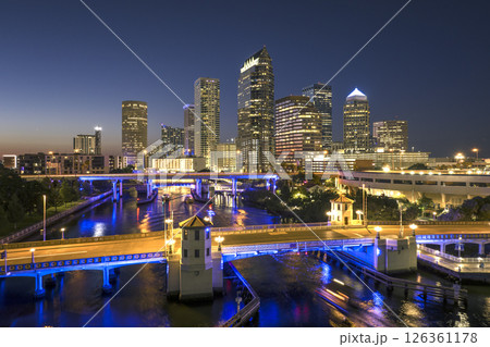 Tampa city in Florida with brightly illuminated highway traffic on bridge and skyscraper buildings in downtown district. American megapolis with business financial district at night Tampa city in Florida with brightly illuminated highway traffic on bridge and skyscraper buildings in downtown district. American megapolis with business financial district at night 126361178