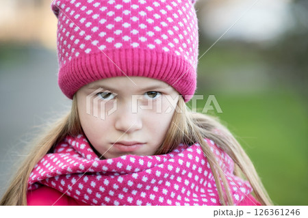 Sad child girl in warm knitted winter clothes outdoors. Sad child girl in warm knitted winter clothes outdoors. 126361246