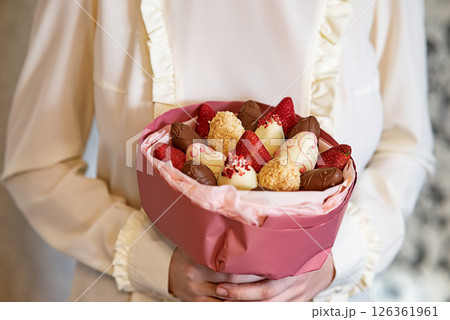 Delicious bouquet with chocolates and strawberries held by a person in a stylish setting 126361961