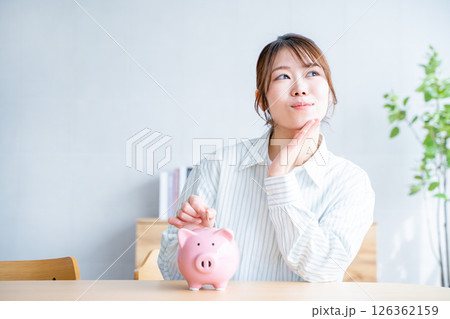 貯金箱に硬貨を入れる女性 126362159