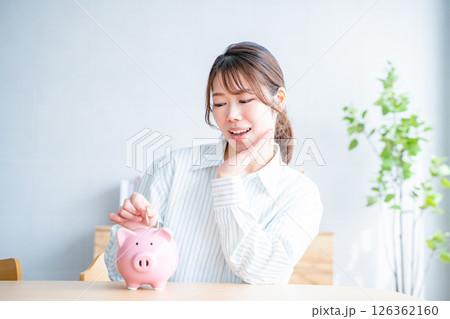 貯金箱に硬貨を入れる女性 貯金箱に硬貨を入れる女性 126362160