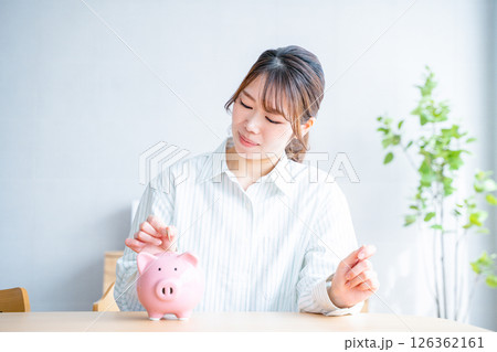 貯金箱に硬貨を入れる女性 貯金箱に硬貨を入れる女性 126362161