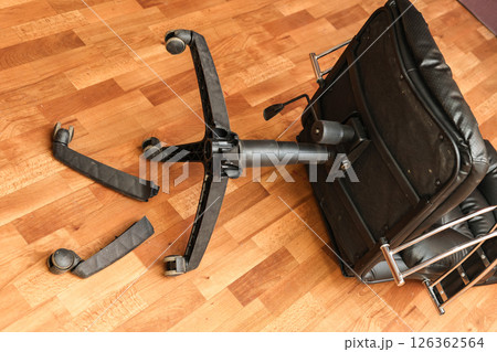 An office chair on the floor with broken legs: a symbol of poor workmanship and the need for repairs 126362564
