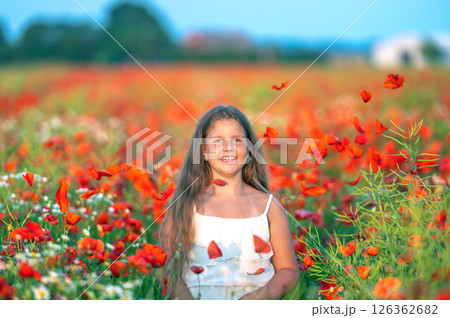 cute girl wearing white dress in summer blooming poppy field playing under evening sun 126362682