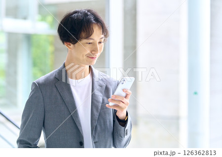 オフィスでスマホを操作するビジネスカジュアルの男性エンジニア 126362813