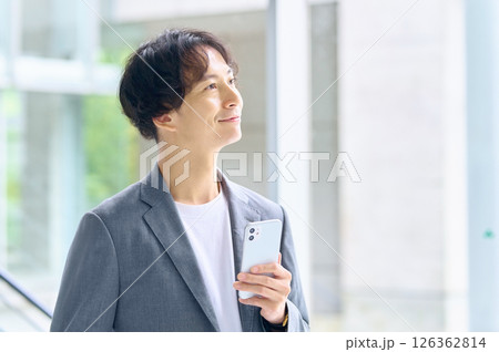 オフィスでスマホを操作するビジネスカジュアルの男性エンジニア オフィスでスマホを操作するビジネスカジュアルの男性エンジニア 126362814