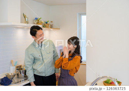 キッチンで並ぶ作業服の日本人男性と主婦の女性 126363725