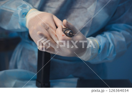 Close-up of a veterinary surgeon's hands holding a surgical drill during a medical procedure, highlighting the precision and concentration in veterinary medicine. Orthopedic surgery on an animal. Close-up of a veterinary surgeon's hands holding a surgical drill during a medical procedure, highlighting the precision and concentration in veterinary medicine. Orthopedic surgery on an animal. 126364034
