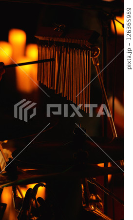 A close-up photo of a drum set with a cymbal and chimes in the foreground. The background is blurred and orange. 126365989