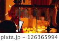 A close-up of a drum set with cymbals and chimes in the foreground, with a blurred background of a musical performance. The background is blurred and orange. 126365994