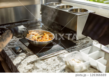 A Chef is Cooking in a Modern Kitchen Using Fresh Ingredients for Delicious Meals A Chef is Cooking in a Modern Kitchen Using Fresh Ingredients for Delicious Meals 126366889
