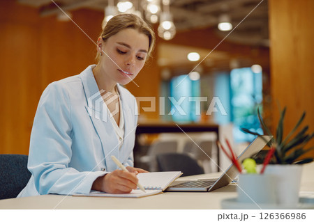 Healthcare Professional Diligently Writing Important Notes Inside a Modern Office Environment 126366986