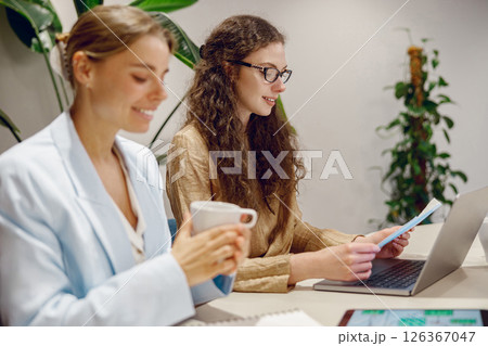A group of professional women collaborating effectively in a modern, vibrant office space A group of professional women collaborating effectively in a modern, vibrant office space 126367047