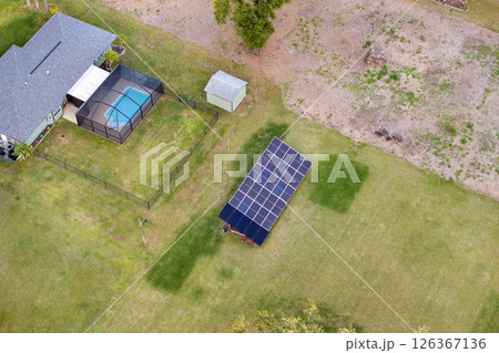 Photovoltaic panels on elevated frame on house backyard for generating of clean electricity Photovoltaic panels on elevated frame on house backyard for generating of clean electricity 126367136