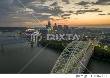 Night urban landscape of downtown district of Cincinnati city in Ohio, USA. Skyline with driving cars on bridge and brightly illuminated high skyscraper buildings in modern American megapolis Night urban landscape of downtown district of Cincinnati city in Ohio, USA. Skyline with driving cars on bridge and brightly illuminated high skyscraper buildings in modern American megapolis 126367155