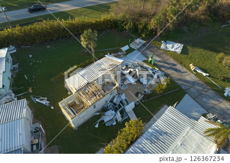 Hurricane strong wind destroyed suburban house roofs in Florida mobile home residential area. Consequences of natural disaster 126367234