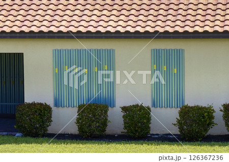 Hurricane shutters made from steel mounted for protection of house windows. Protective measures before natural disaster in Florida 126367236