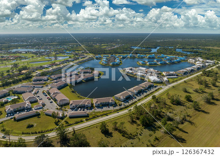 Hurricane damaged apartment buildings rooftops covered with protective plastic tarp against rain water leaking until replacement of asphalt shingles. Aftermath of natural disaster Hurricane damaged apartment buildings rooftops covered with protective plastic tarp against rain water leaking until replacement of asphalt shingles. Aftermath of natural disaster 126367432