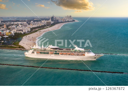 Cruise ship leaving Miami harbor main channel near South Beach. Luxurious hotels and apartment buildings on waterfront and high skyscrapers of downtown district in distance 126367872
