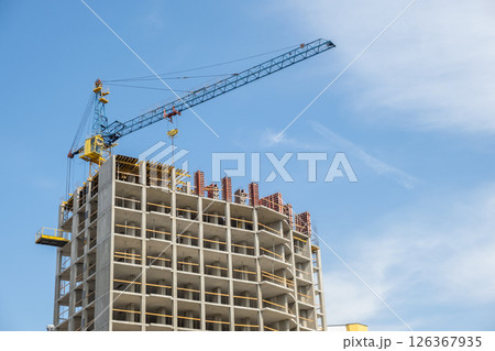 Concrete frame of tall apartment building under construction and tower crane in a city. 126367935