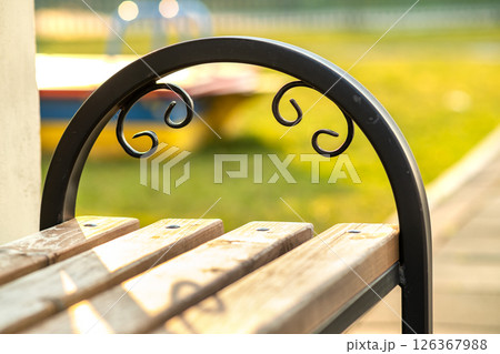 Closeup of wooden park bench with metal handgrip outdoors. 126367988
