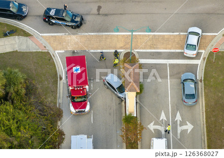 Car crash site with emergency services personnel and vehicles responding to accident on American street. First responders helping victims of vehicle collision on road in USA 126368027