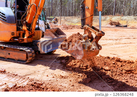 Heavy machinery is digs trench moving dirt at construction site 126368248