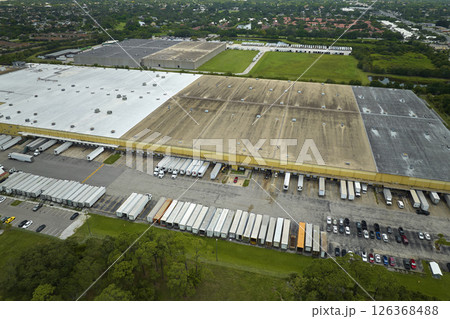 Big corporate shipment center with many cargo semi trucks unloading and uploading retail products for further retail shipment. Global market concept 126368488