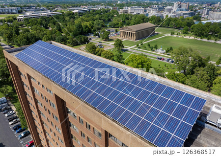 Apartment building with solar roof. Blue photovoltaic panels for producing clean ecological electric energy. Investing in renewable electricity concept Apartment building with solar roof. Blue photovoltaic panels for producing clean ecological electric energy. Investing in renewable electricity concept 126368517