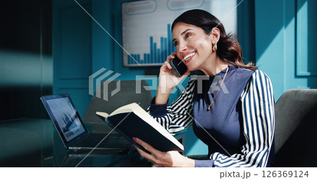 Office, businesswoman and notebook with phone call for talking, negotiation and laptop for finance. Career, mature person and financial analyst with statistics for mobile discussion, notes and smile Office, businesswoman and notebook with phone call for talking, negotiation and laptop for finance. Career, mature person and financial analyst with statistics for mobile discussion, notes and smile 126369124